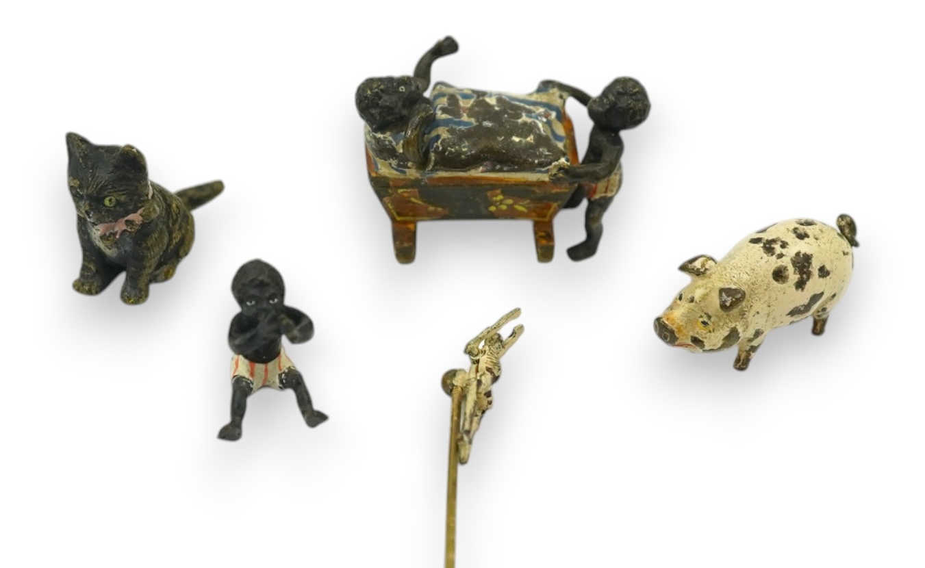 Four novelty miniature cold painted bronzes; black boy with cradle, black baby, cat and pig and a similar articulated arm skeleton stickpin,7cm long. Condition - some chipping to paint